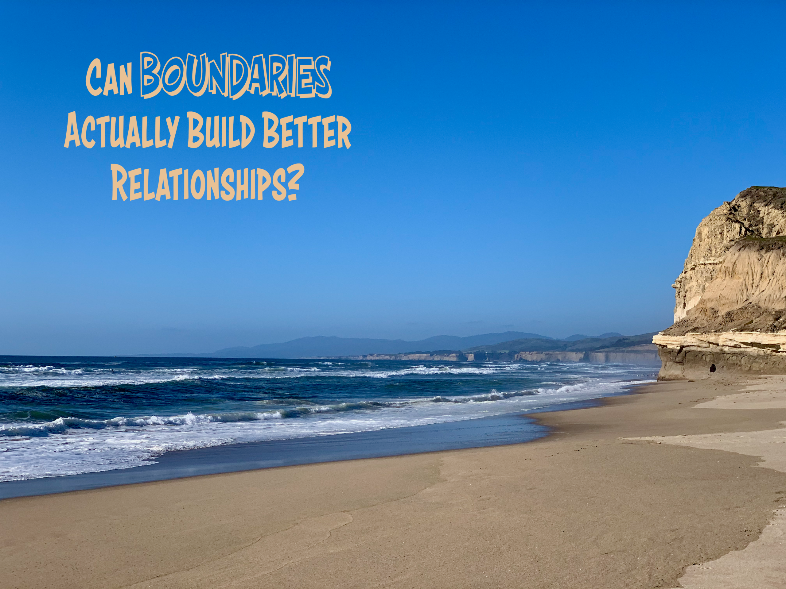 Rocky coastline where ocean waves meet the sandy shore beneath a blue sky, with the words “Can Boundaries Actually Build Better Relationships?”